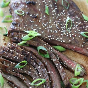 Cooked steak garnished with green onions and sesame seeds that was first marinated with Asian Beef Marinade recipe.