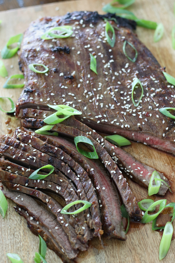 Cooked steak garnished with green onions and sesame seeds that was first marinated with Asian Beef Marinade recipe.