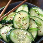 Asian Cucumber Salad served a grey bowl with wooden chopsticks.