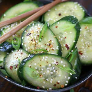 A large serving of Asian Cucumber Recipe served in a grey bowl sitting on a wooden table.