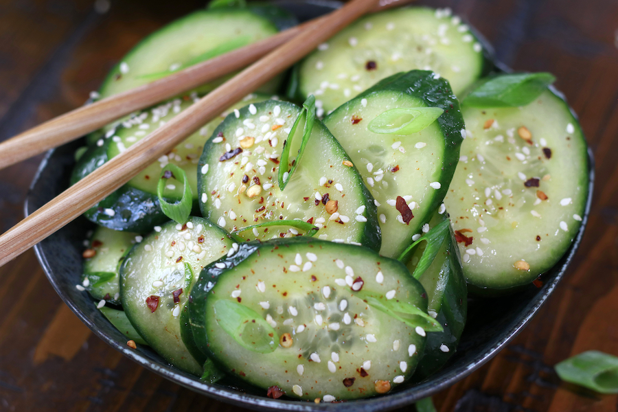 A large serving of Asian Cucumber Recipe served in a grey bowl sitting on a wooden table.