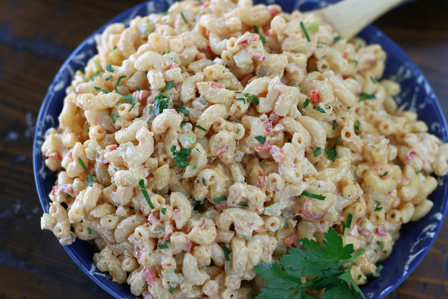 Mac Salad in a blue bowl sitting on a brown wooden table.