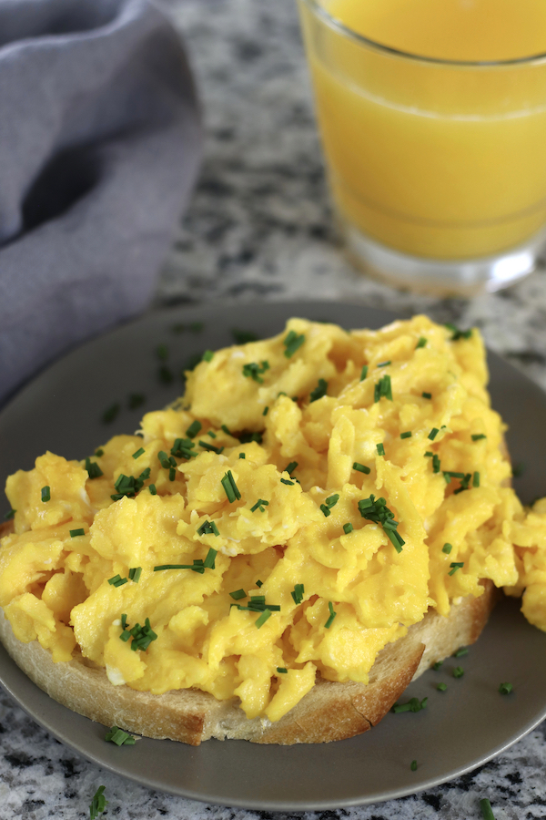 Scrambled Eggs on bread served net to orange juice.