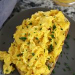 Scrambled Eggs on toast sitting on a grey plate.