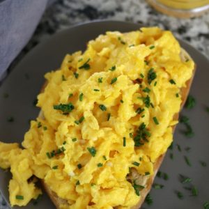 Scrambled Eggs on toast sitting on a grey plate.