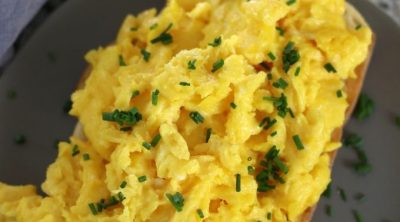 Scrambled Eggs on toast sitting on a grey plate.