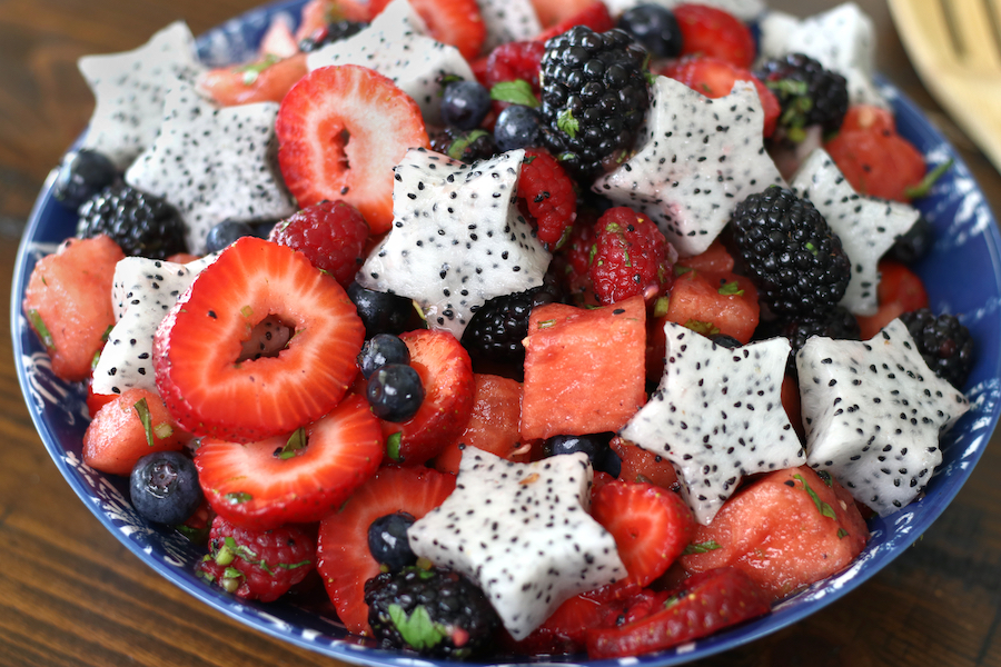 Berry Salad in a blue bowl sitting on a brown table.