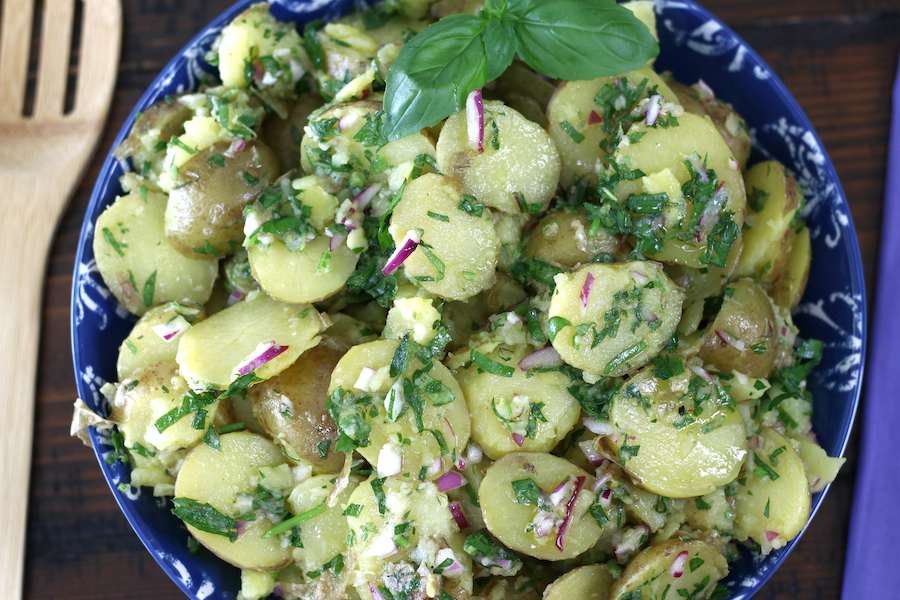 Lemon Potato Salad loaded with freshly chopped herbs and garnished with basil leaves.