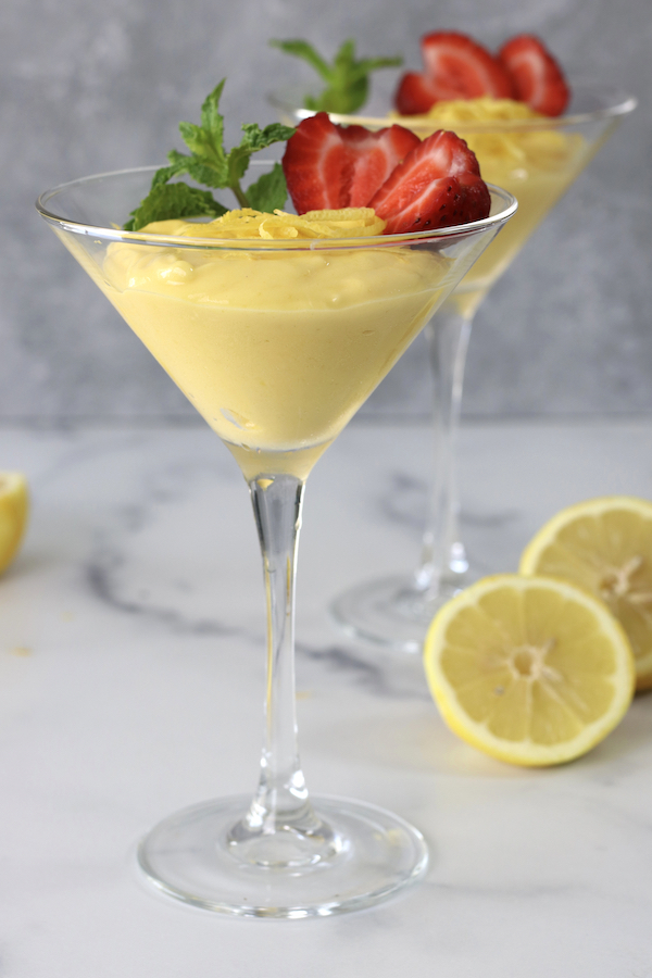 Martini glasses filled with Lemon Zabaglione sitting on a white countertop.