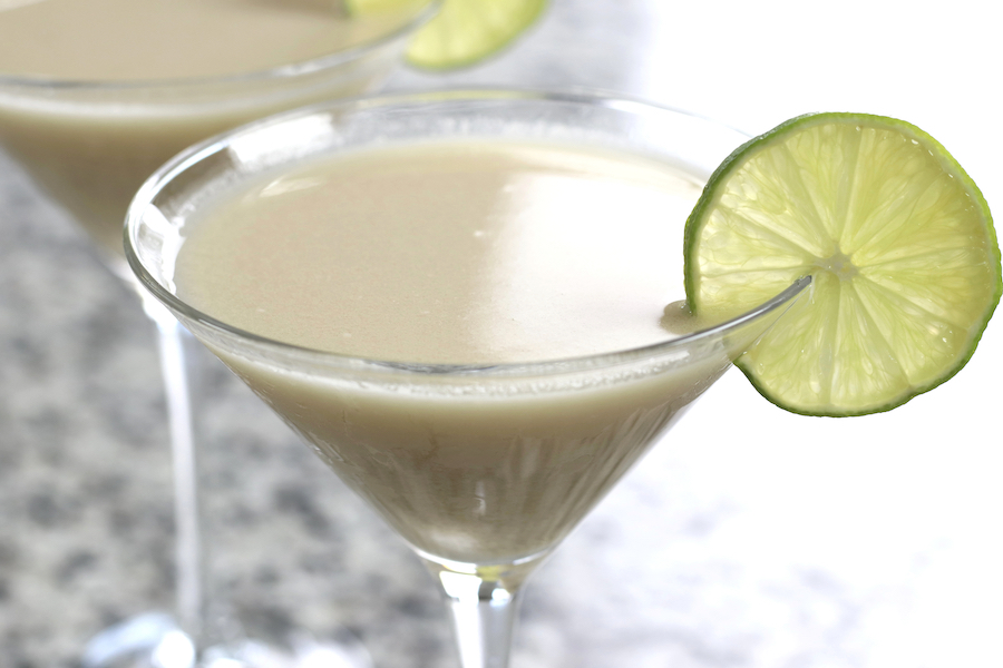 Side shot of Key Lime Martini Recipe in a martini glass with a lime wedge.