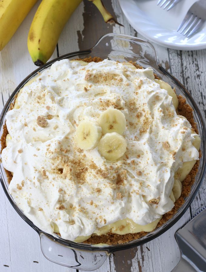 Overhead photo of a Banana Cream Pie sitting on a wooden table.
