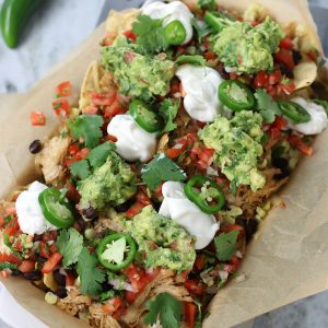 A pan of Pulled Chicken Nachos sitting on a metal trivet.