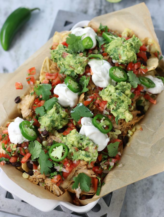 Overhead photo of Shredded Chicken Nachos loaded with Pico de Gallo, Guacamole and sour cream.