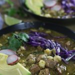 Pozole Verde garnished with avocado, radish slices and shredded red cabbage.