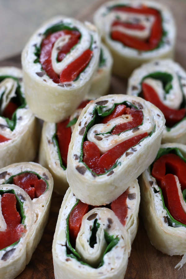 Tortilla Rolls Ups with cream cheese and spinach stacked on top of each other.