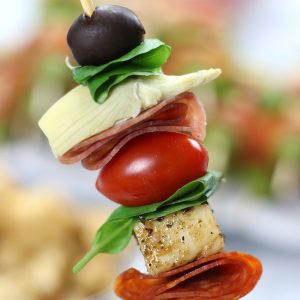 Up close photo of a person holding an Antipasto on a Stick.