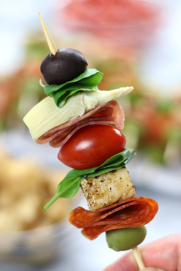Up close photo of a person holding an Antipasto on a Stick.