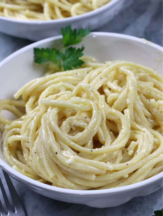 A big bowl of Alfredo sauce served on bucatini pasta.