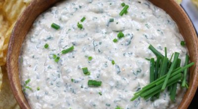 Roasted Garlic Dip served in a brown bowl and garnished with fresh chives.
