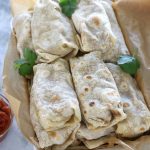 Bean and Cheese Burritos lined up in a pan before freezing.