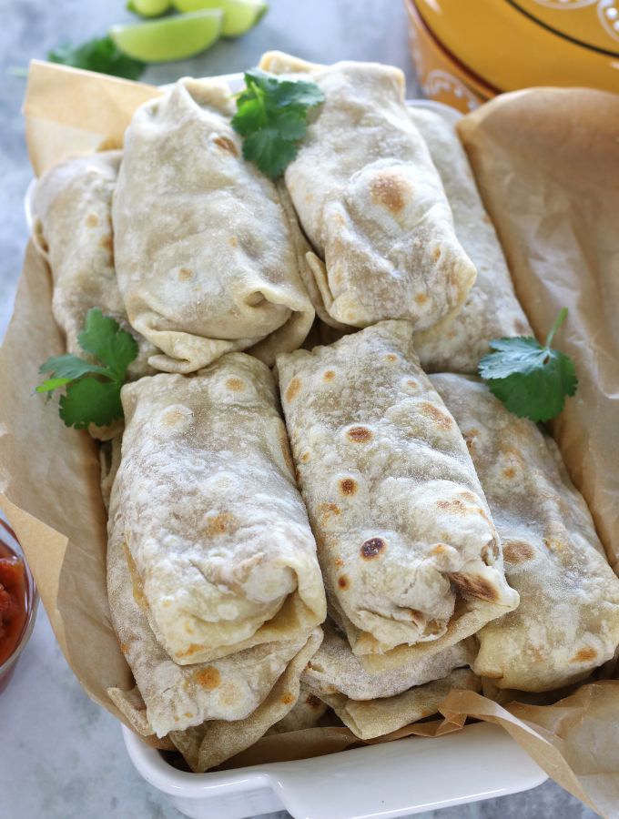 Overhead photos of Frozen Bean and Cheese Burritos piled in a roasting pan before freezing.