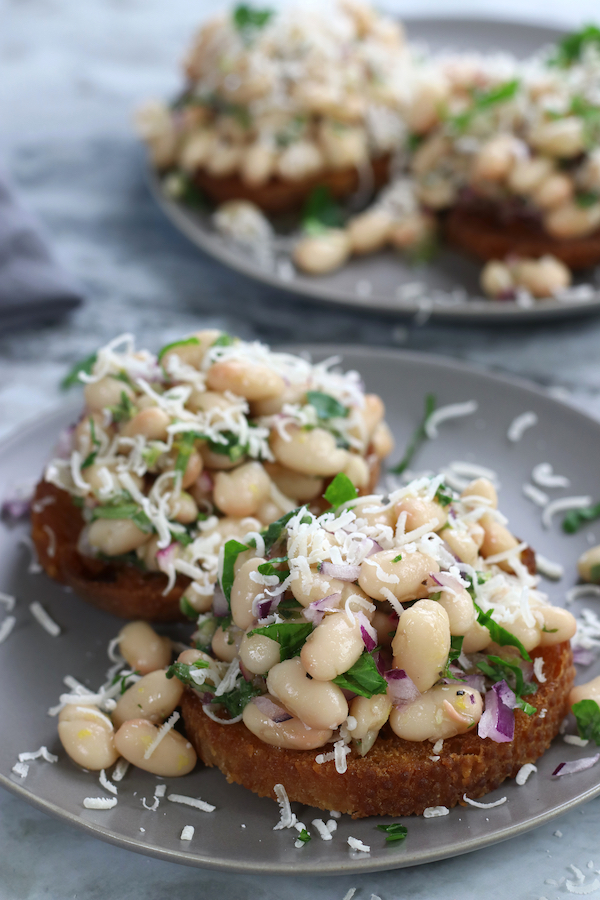 Marinated Cannellini Beans on toast served on grey plates.