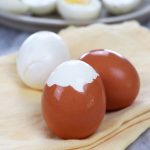 Three Easy Peel Hard Boiled Eggs with one egg fully peeled, one partially peeled and one unpeeled.