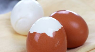 Three Easy Peel Hard Boiled Eggs with one egg fully peeled, one partially peeled and one unpeeled.