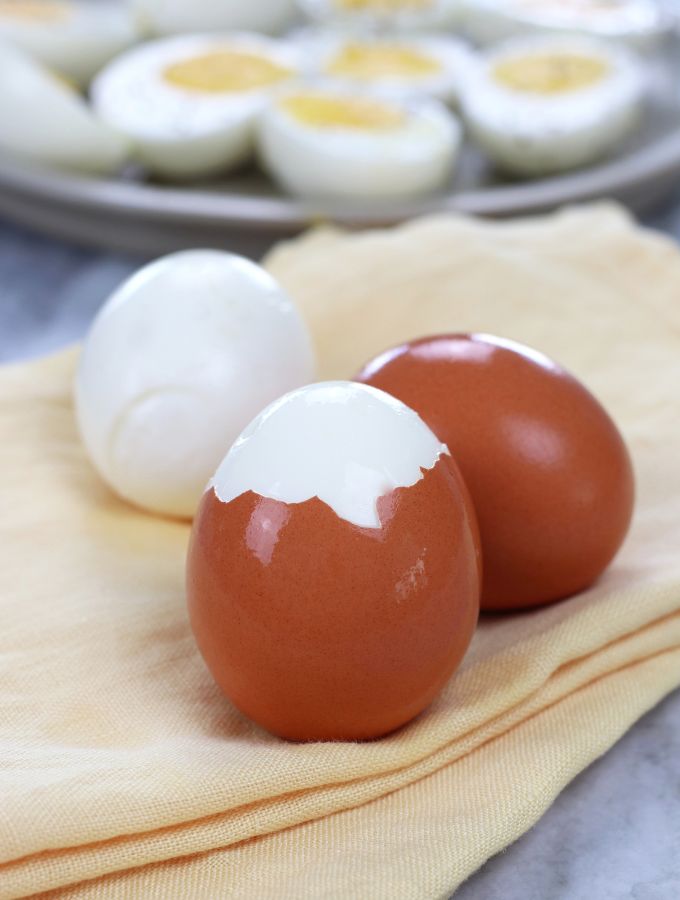 Three Easy Peel Hard Boiled Eggs with one egg fully peeled, one partially peeled and one unpeeled.