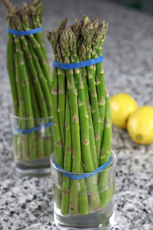 Fresh asparagus sitting upright in a glass of water for the Oven Roasted Asparagus recipe.