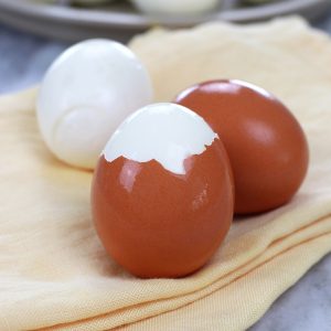 Hard Boiled Eggs sitting on yellow cloth napkins with shells on a few of the eggs.