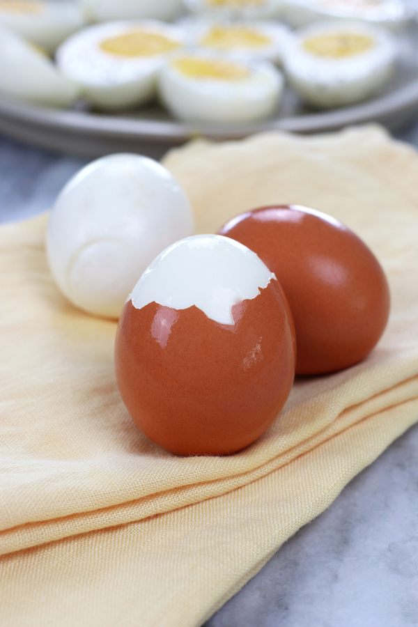 Hard Boiled Eggs sitting on yellow cloth napkins with shells on a few of the eggs.