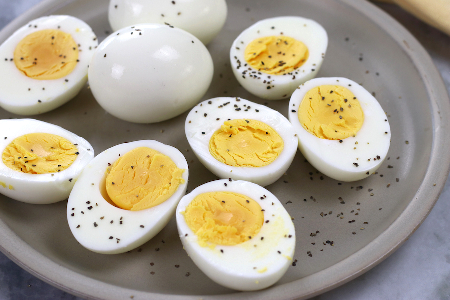 Steam Boiled Eggs cut in half and sitting on a small tan plate garnished with black pepper.