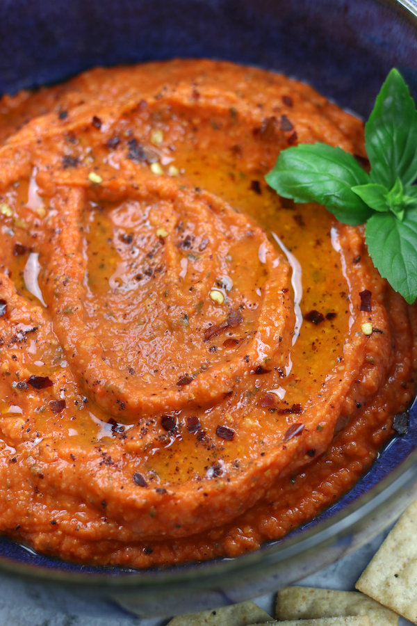 Very up close photo of White Bean Red Pepper Dip made shiny with a drizzle of olive oil.