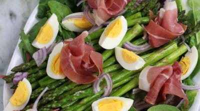 Overhead photo of Asparagus Salad with Egg and Prosciutto on an oval white platter.