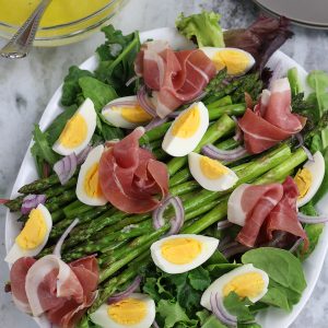 Asparagus and Egg Salad on a white platter sitting on a white marble countertop.