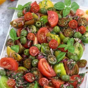 Heritage Tomato Salad served on a platter sitting on a white countertop.