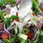 Homemade Creamy Italian Dressing being drizzled over an Italian salad.