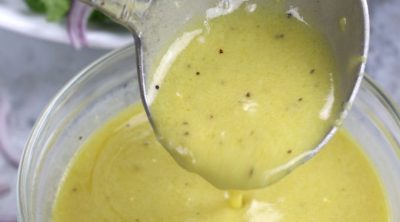 A small ladle spooning Lemon Dijon Dressing.