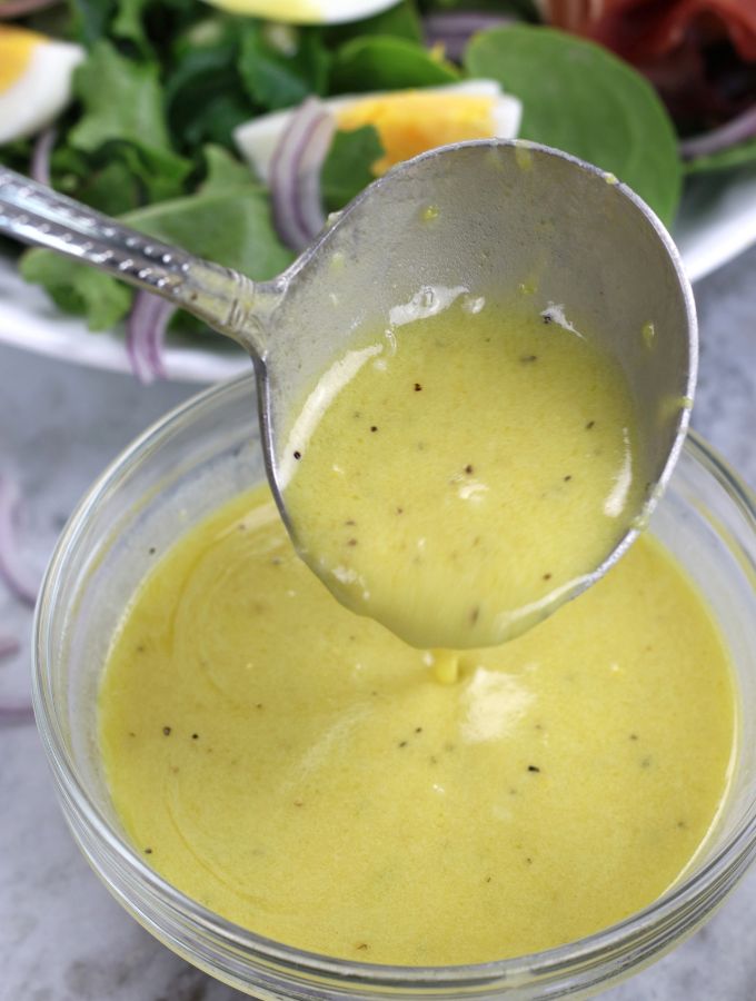 A small ladle spooning Lemon Dijon Dressing.