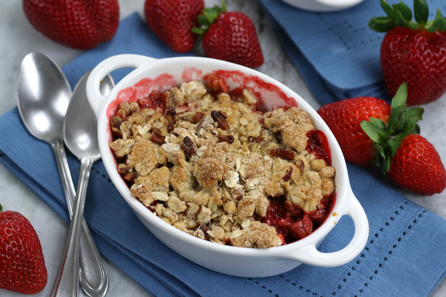 An individual serving of Easy Strawberry Crumble surrounded by fresh strawberries.