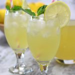 Two chalice glasses of lemonade sitting on a marble countertop from How To Make Lemonade recipe.