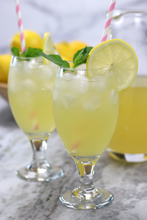 Two chalice glasses of lemonade sitting on a marble countertop from How To Make Lemonade recipe.