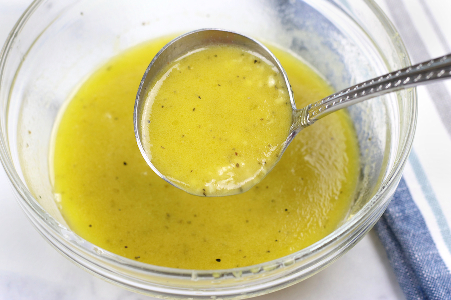 A spoon dipping into a bowl of White Balsamic Vinegar Dressing.