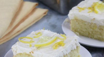 Two slices of Lemon Sheet Cake served on small white plates.