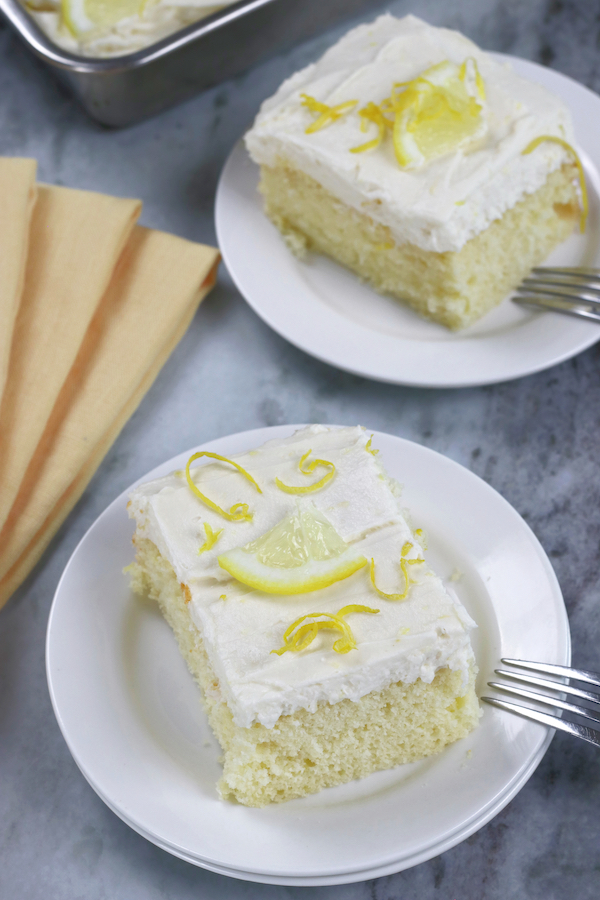 Overhead photo of slices of Lemon Sheet Cake with Cream Cheese Frosting served on small white plates.