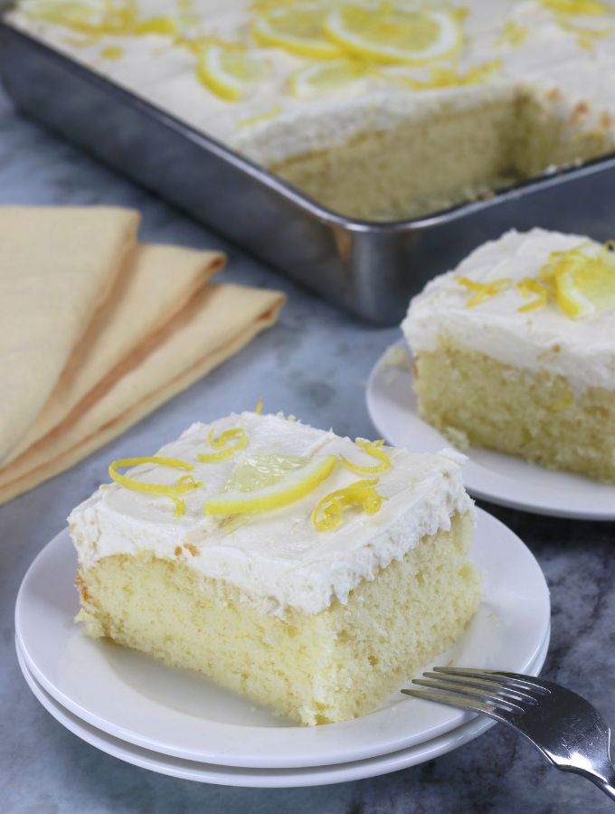 Two slices of Lemon Sheet Cake served on small white plates.