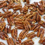 Maple Candied Pecans resting on parchment paper.