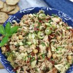 Mediterranean Chicken Salad Sandwich filling in a blue bowl garnished with basil leaves.