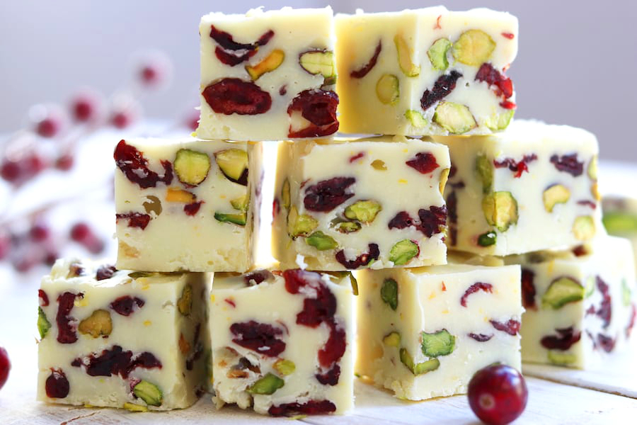 Cranberry Pistachio Fudge flavored with orange stacked three high on a white wooden table.